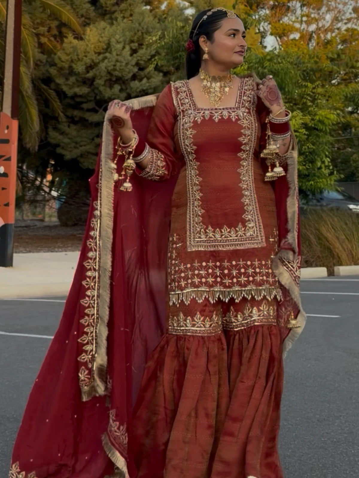 Burgundy bridal suit with ornate gold embroidery and a matching dupatta