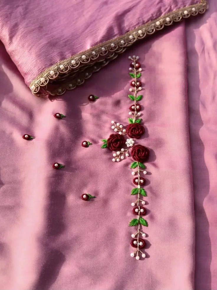 Close-up of pink fabric with floral embroidery and decorative trim